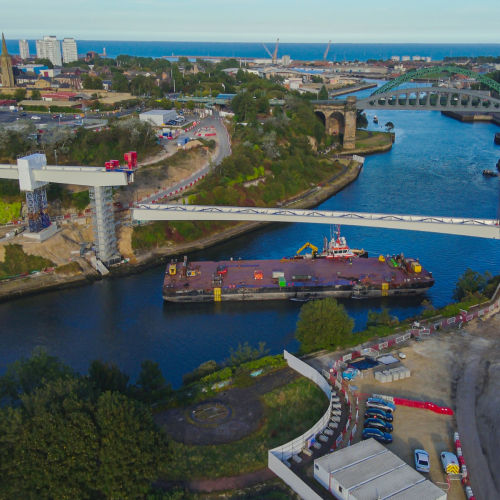 A barge on a river going under a bridge. 