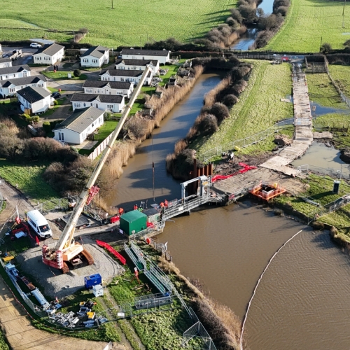 A river with a crane on a bridge.