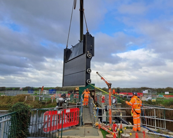 Large flood gate being lifted into position on construction site