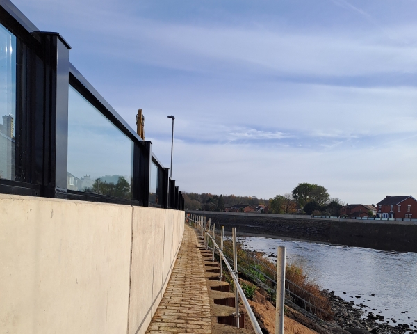 Glass flood panels a top a concrete wall by a river